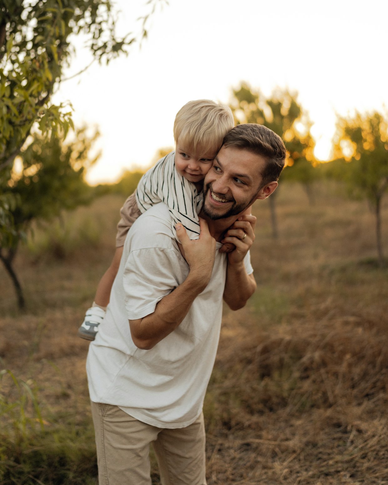 A father carrying his small son on his shoulders in the last of the evening light.
